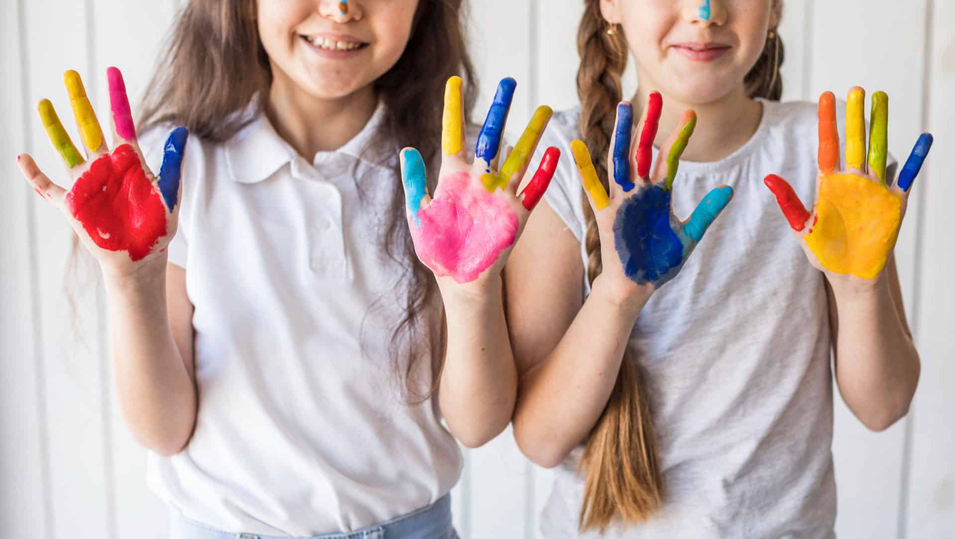 close-up-smiling-two-girls-showing-their-painted-hands-with-color